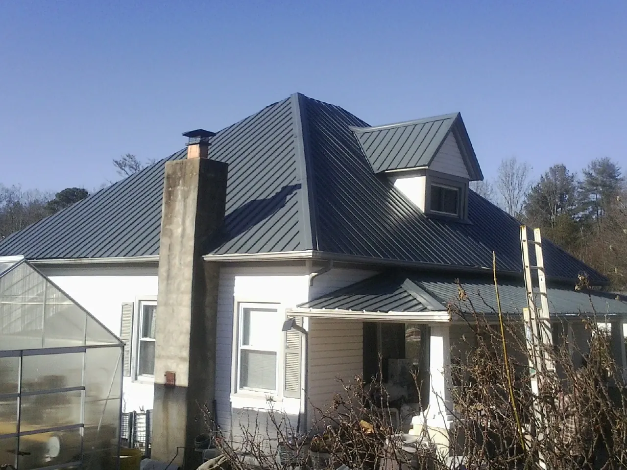 Dark blue standing seam metal roof on a white farmhouse with dormer — Slate & Tile Roof Repair by Roofing Brothers in Lake Elmo