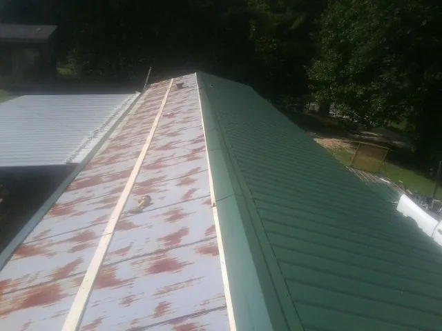 Old rusted panels beside newly installed green metal roofing — Wind Damage Roof Repair by Roofing Brothers in Lake Elmo