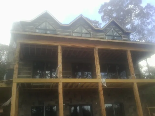 Dormers and porch framing on a large log home under construction — Roof Coating work by our crew in Lake Elmo
