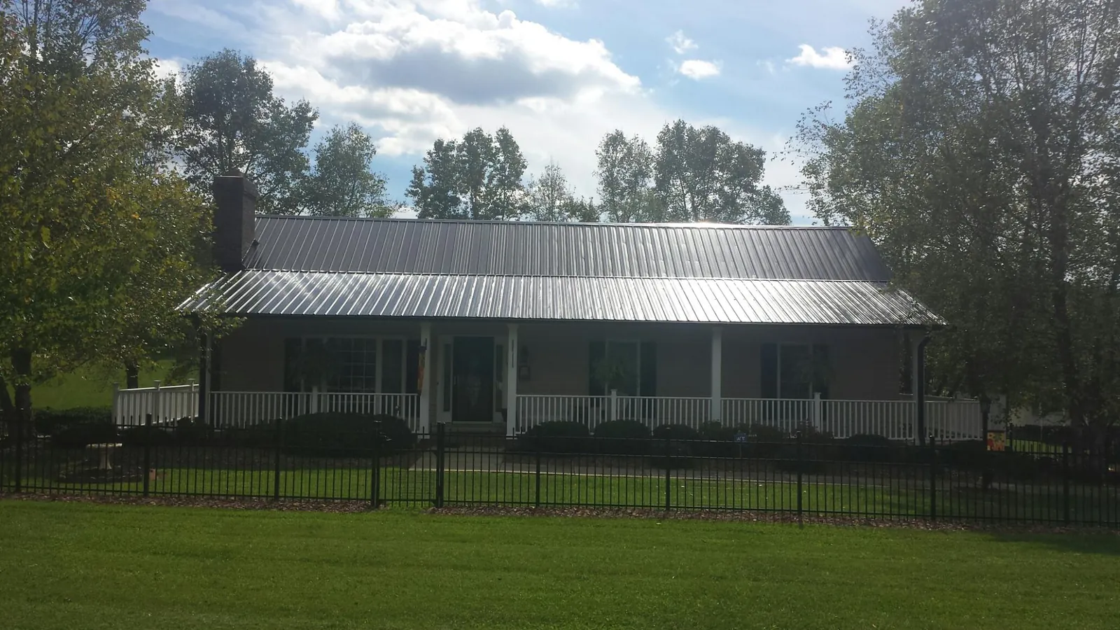 Gray metal roof on a brick ranch with a full width front porch — Gutter Guard Installation work by our crew in Lake Elmo