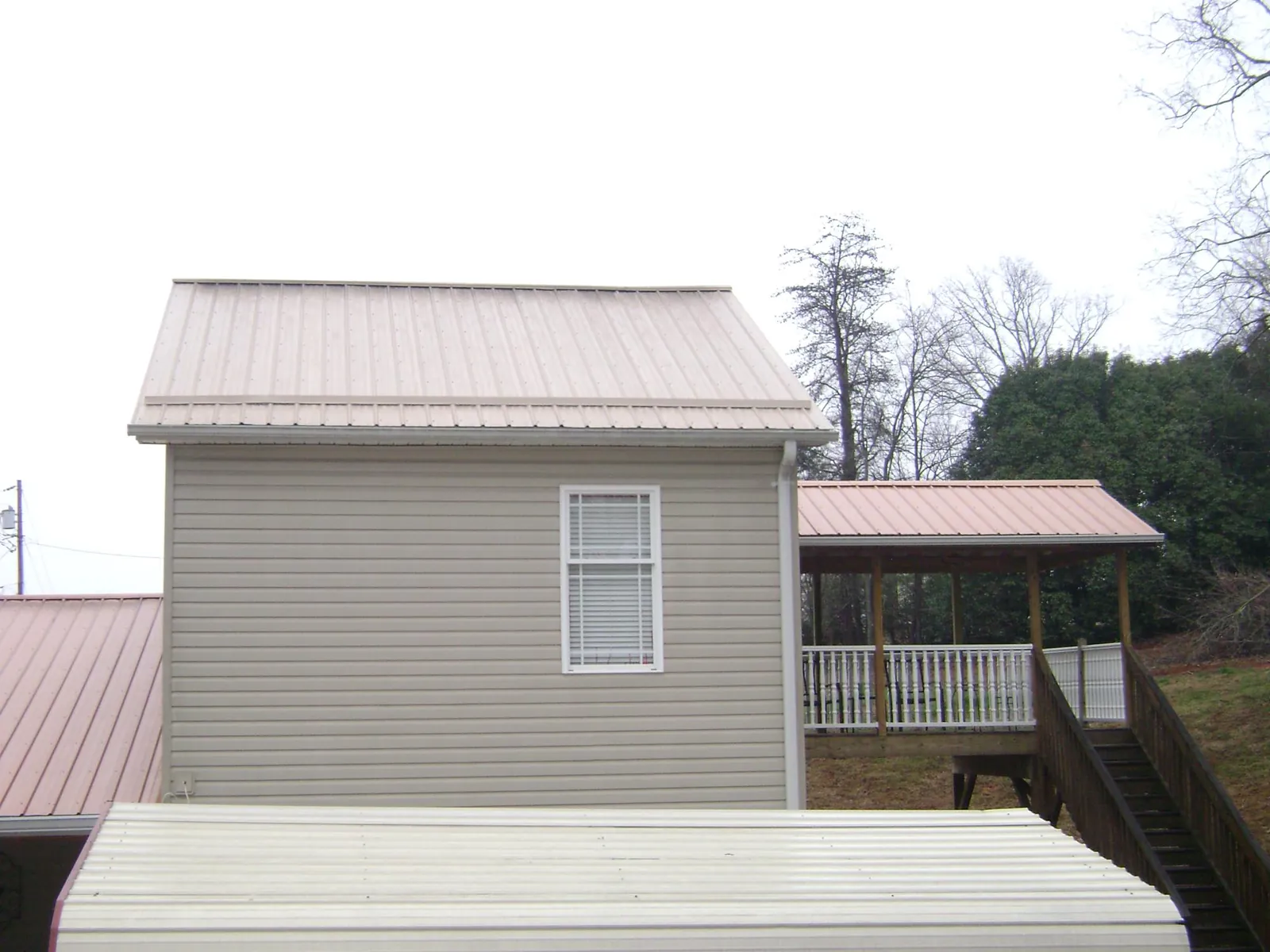 Tan metal roofs on a two story addition and attached porch, from a Roof Replacement job in Lake Elmo