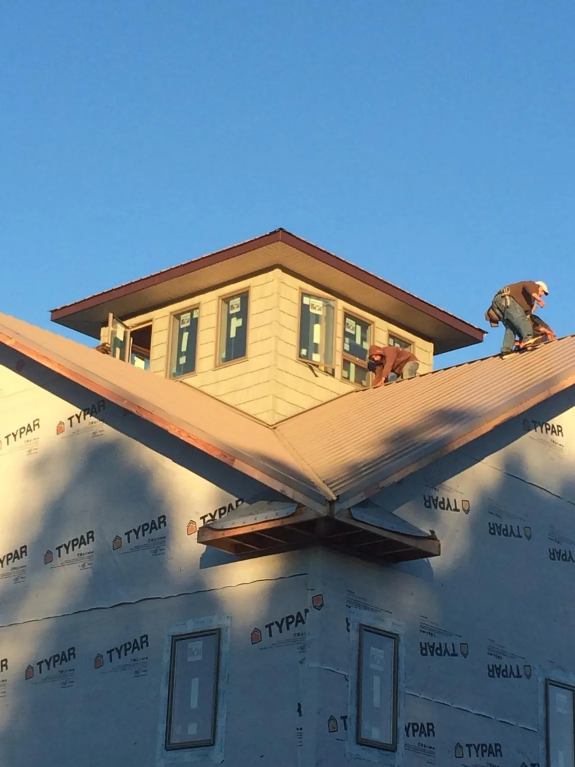 Roofers working around a rooftop cupola on a new metal roof at sunset — Roof Waterproofing in Lake Elmo by Roofing Brothers